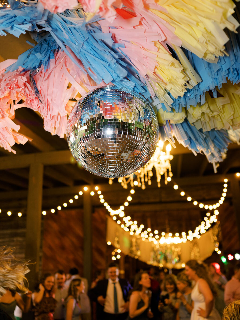 Disco ball at a wedding reception surrounded by colorful streamers
