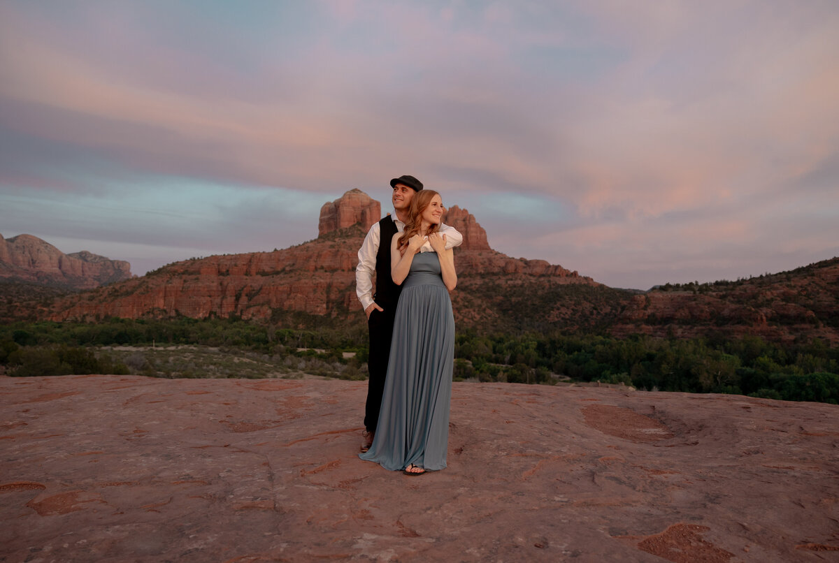 Couple standing against red rock backdrop during Sedona engagement session