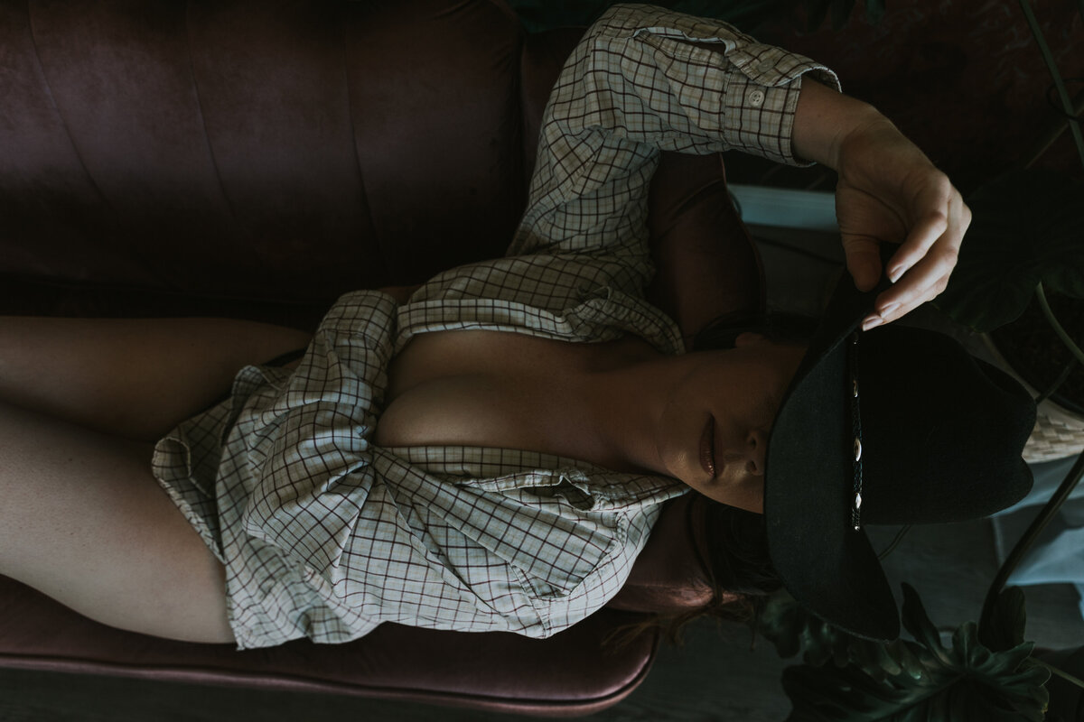 woman wearing a cowgirl hat posed on the couch