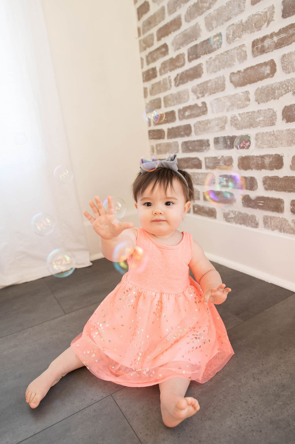A small child sitting on the ground playing with bubbles.