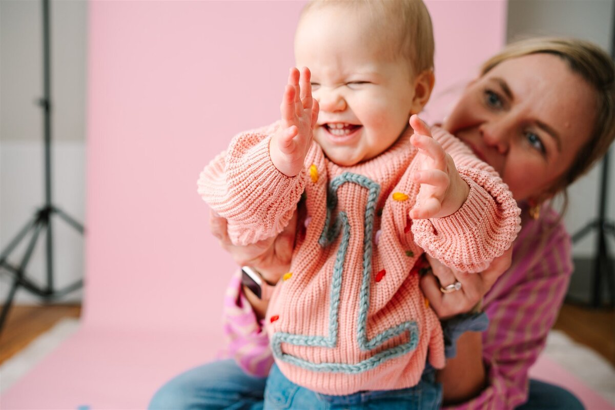 Someone holding up a baby as they laugh and clap 