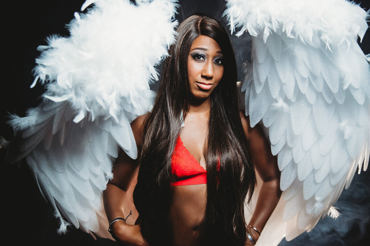 Dark skinned woman in red lingerie and white wings posing