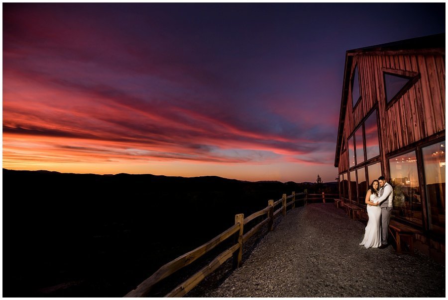 bride and groom in front of barn and beautiful sunset in maine