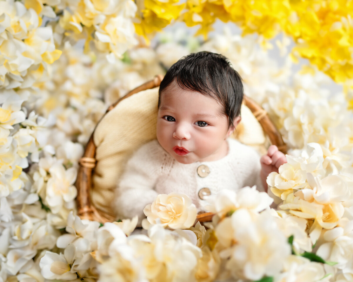 Newborn portrait captured in studio surrounded by soft yellow and ivory florals. A joyful and vibrant floral baby photo from Meraki Photographic Creations in Paris, Ontario.