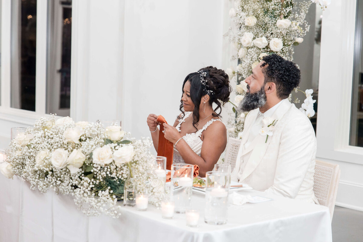 The couple smiles as they raise their glasses in a toast, celebrating their love with family and friends.