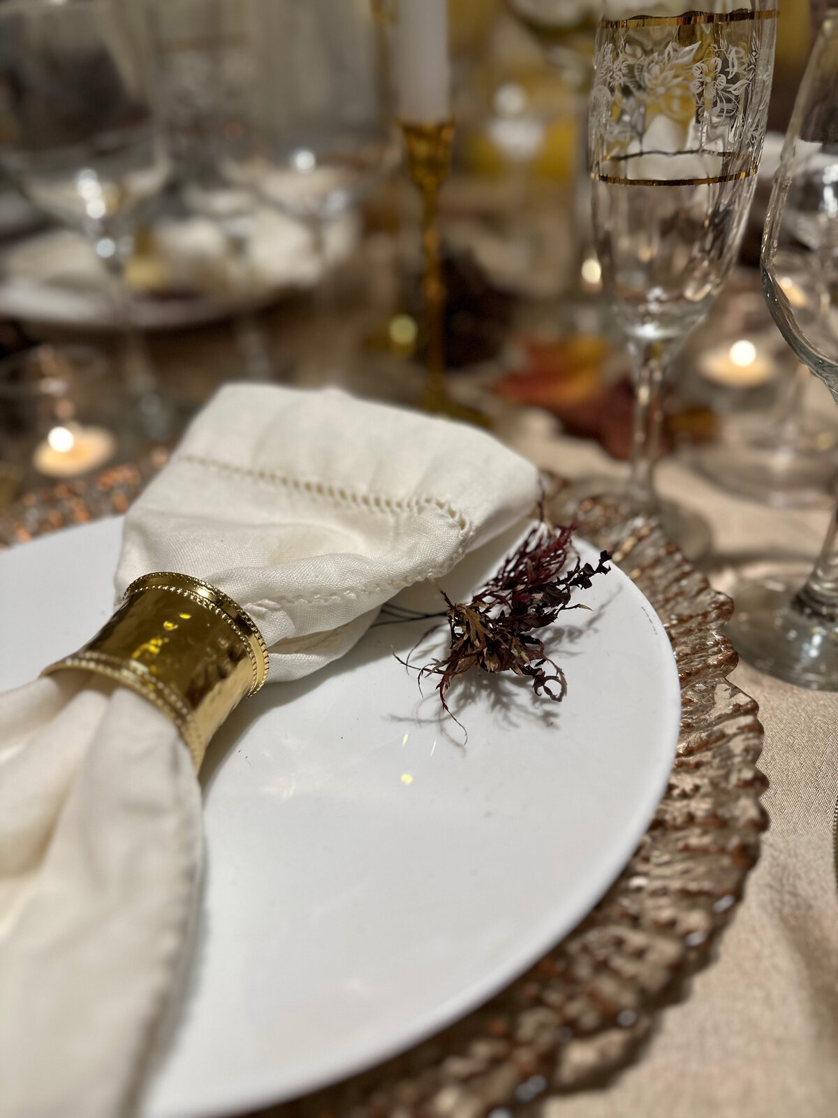 Elegant  dinner tablescape featuring white china, autumn leaves, and warm seasonal accents, creating a cozy and sophisticated holiday setting, designed by In Full Bloom Event Planning & Design