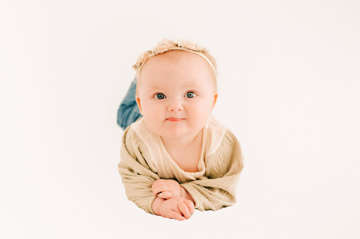 6 month old kid laying on belly making funny face