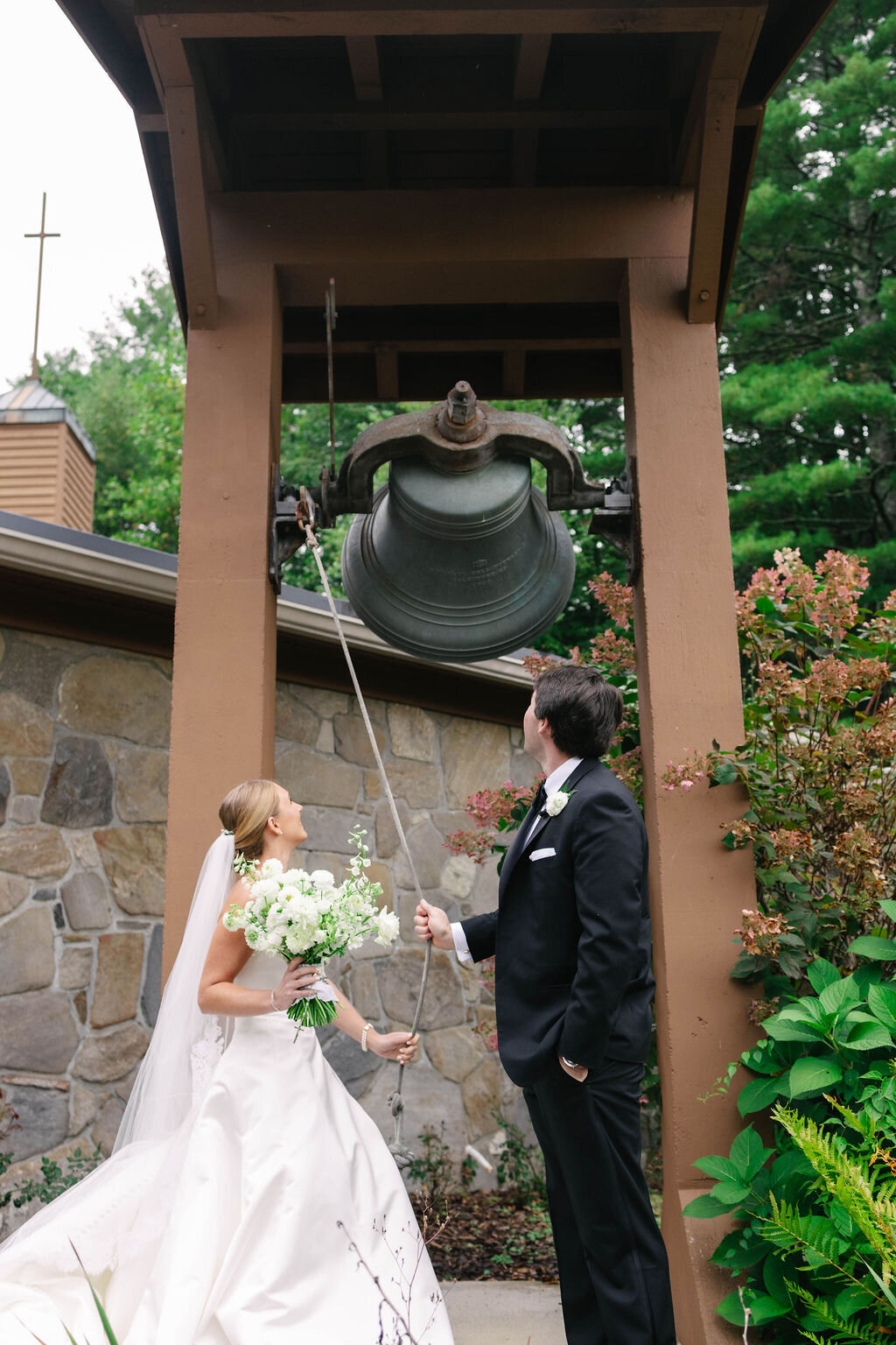 Bride and groom ringing the church bell in celebration after their fall wedding ceremony in Highlands NC.