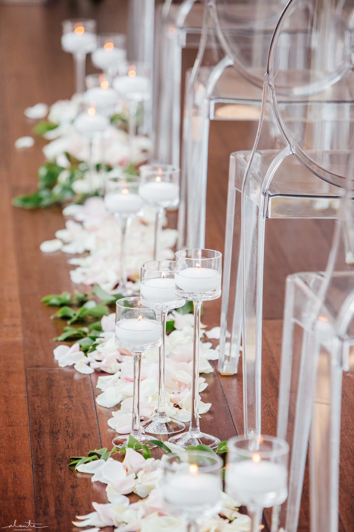 Stemmed hurricane candles and rose petals line the aisle of this wedding ceremony.