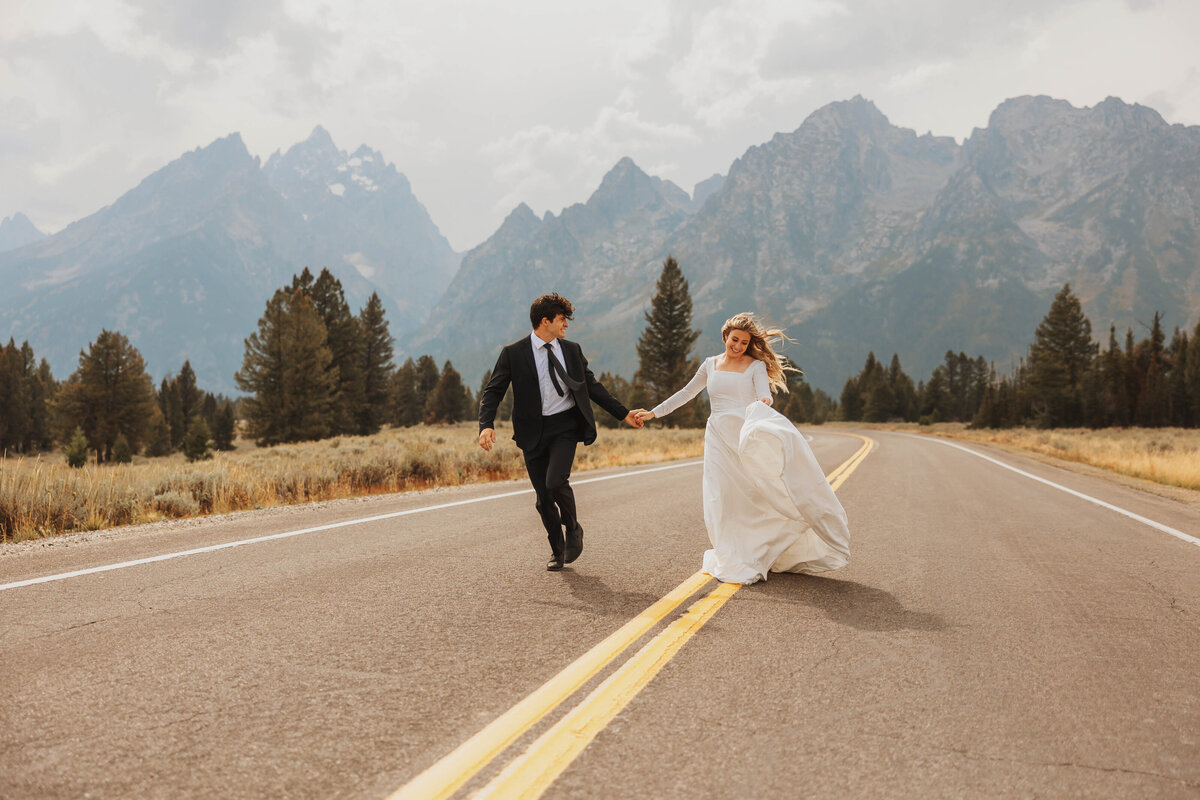 bride and groom holding hands in road
