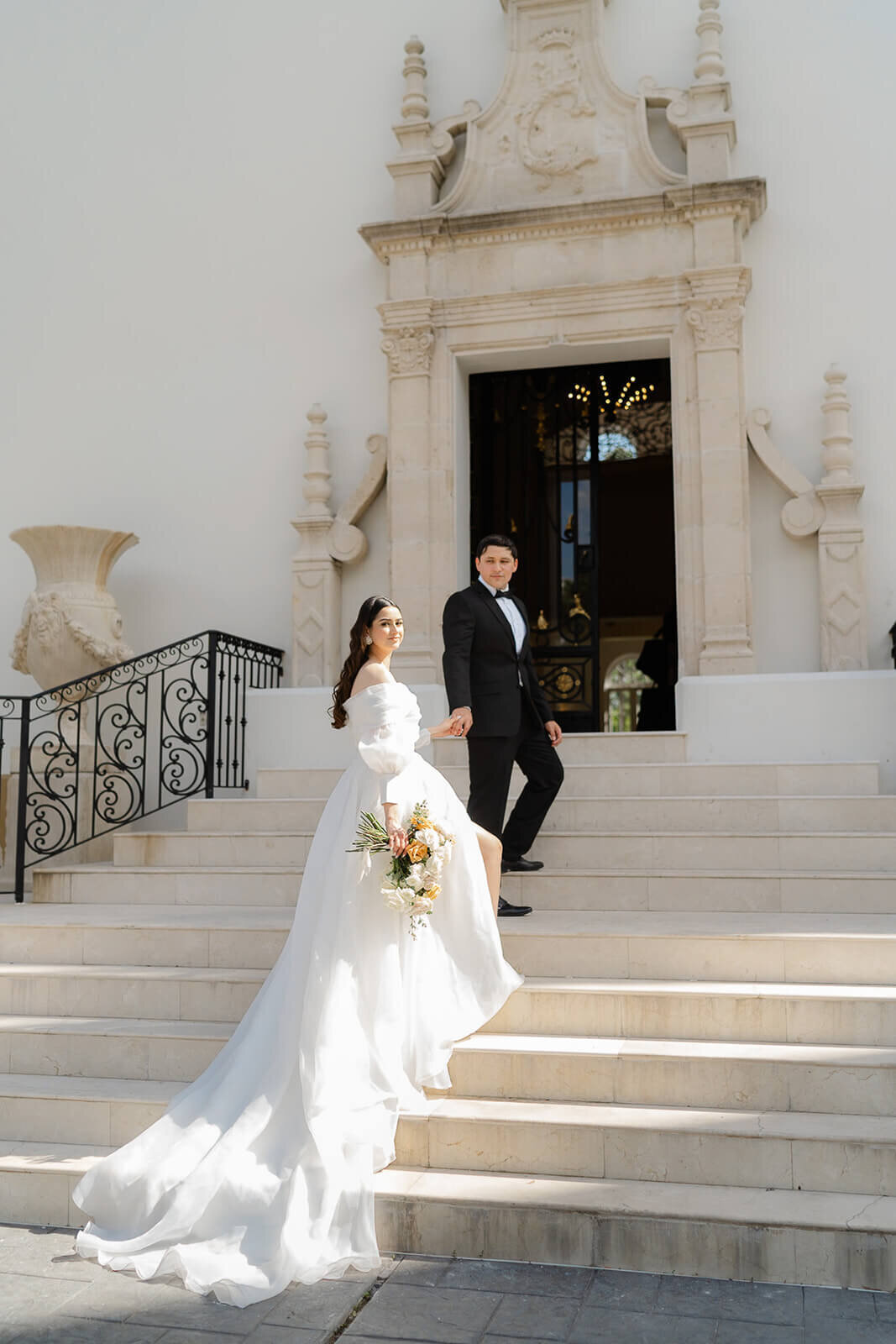 groom leading his bride up the elegant staircase