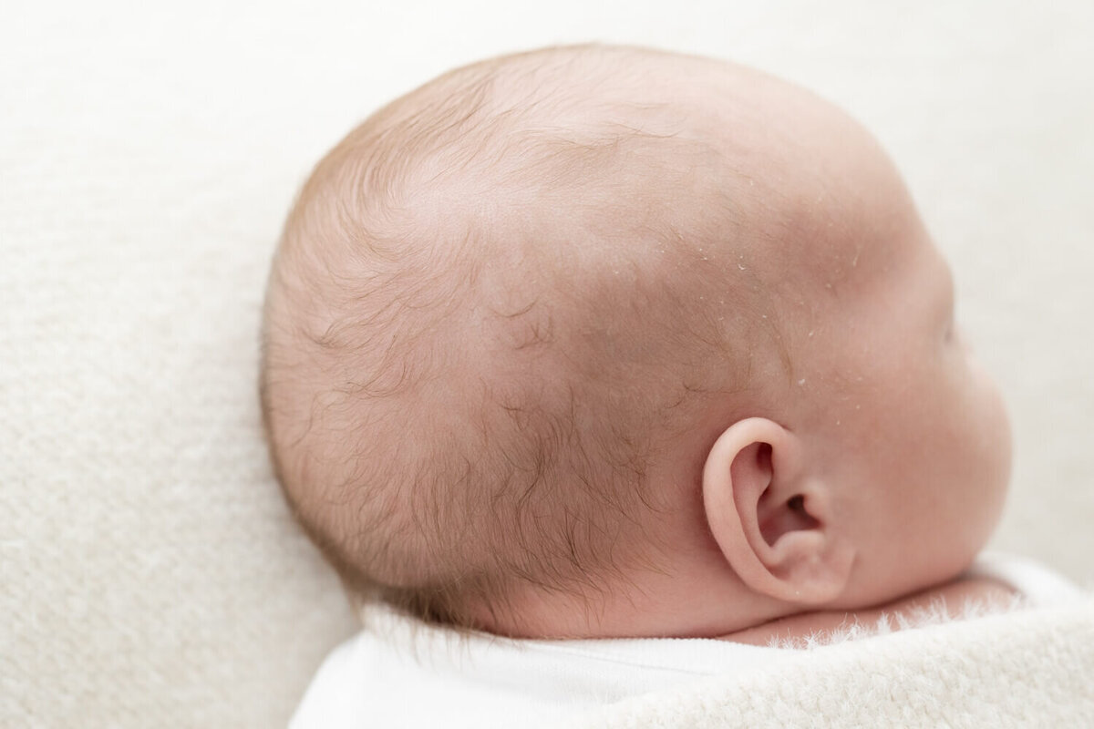 Close-up van zachte haartjes, vastgelegd in een warme setting tijdens een newborn shoot Tilburg.