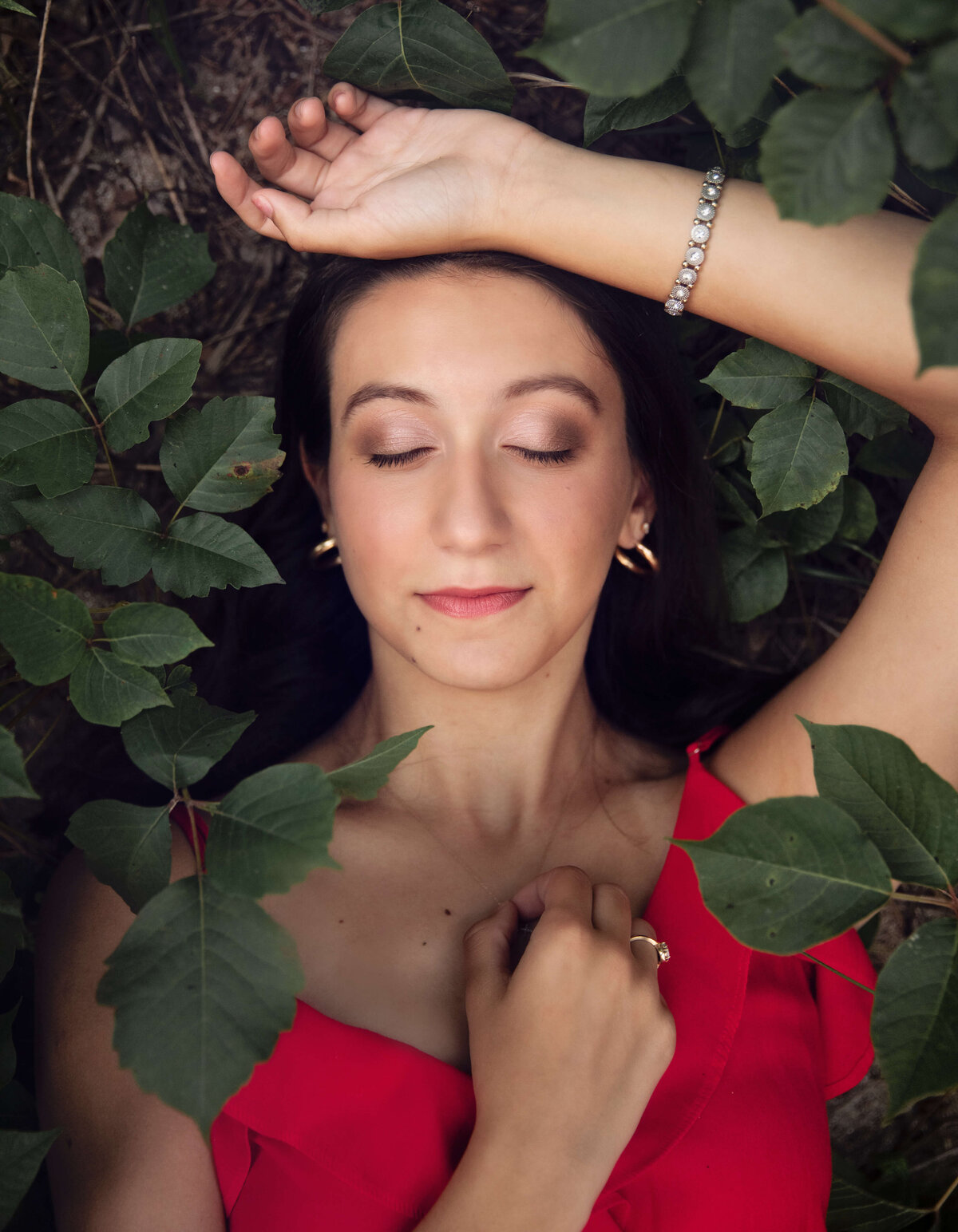 Photo of a senior laying with eyes closed in foliage in Erie Pa