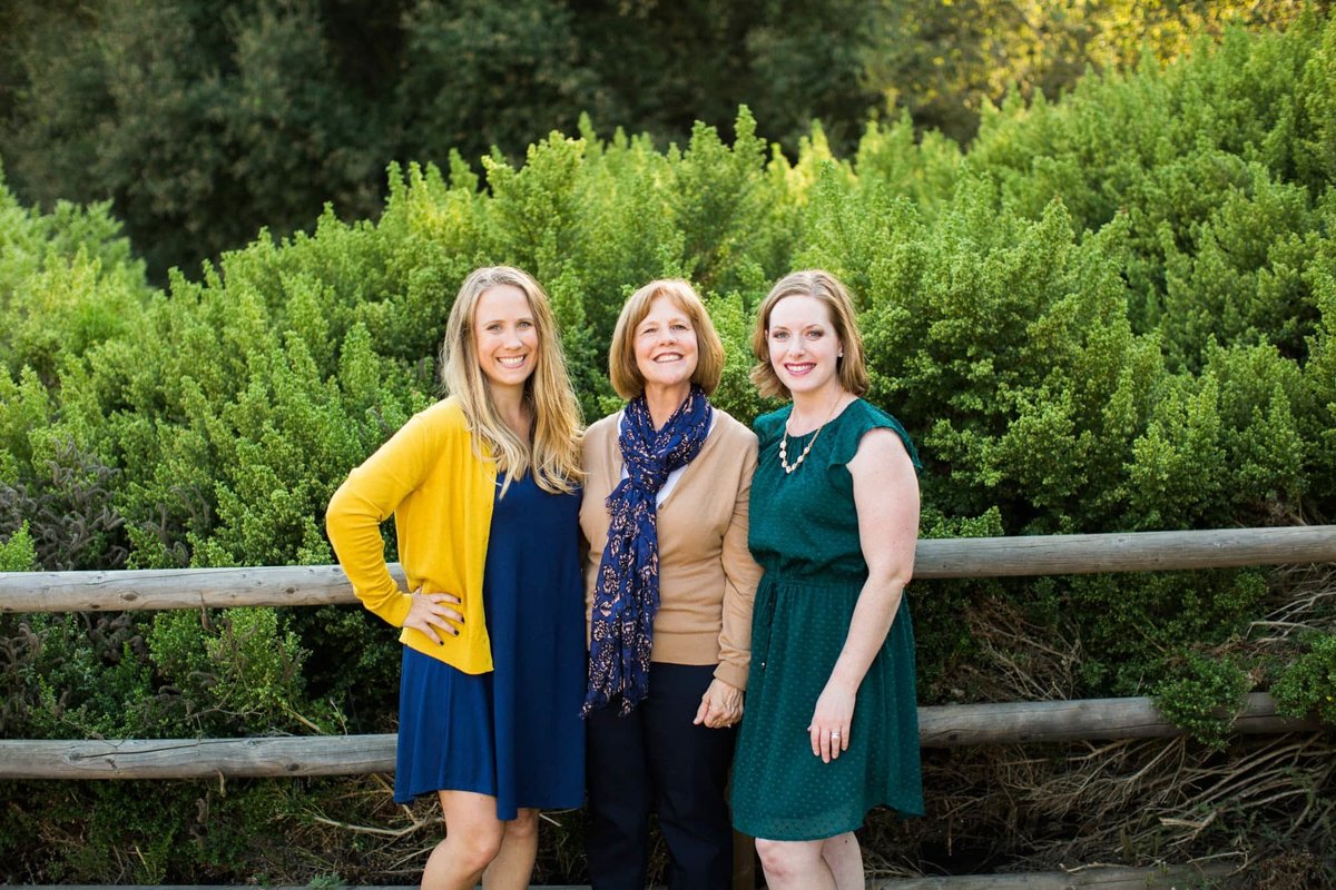 Mother poses with her two adult daughters along a nature trail