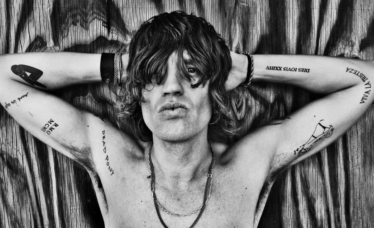 Male musician portrait Nico Stai black and white shirtless with arms behind head wood texture backdrop