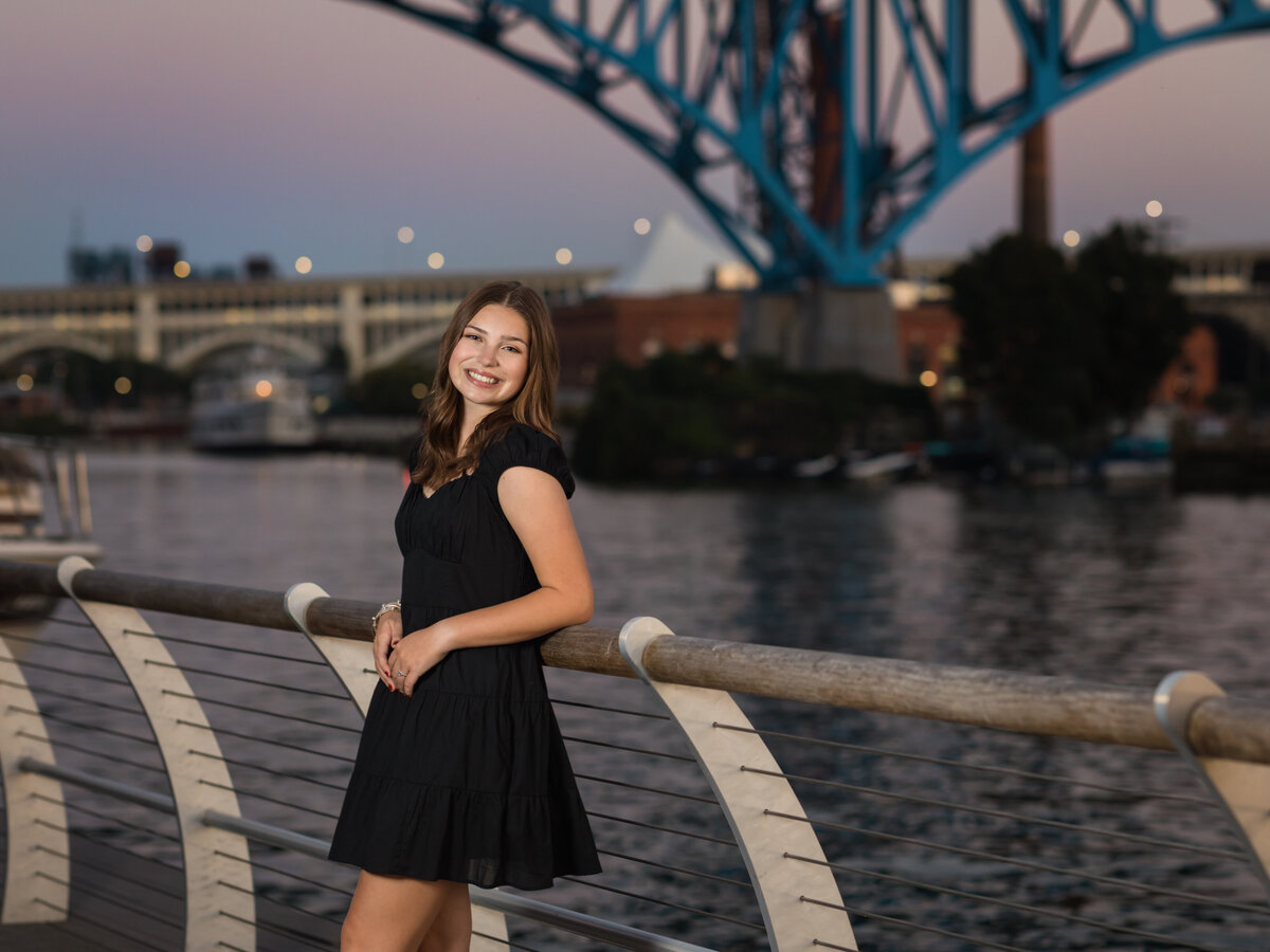 senior girl in black dress posed by water in cleveland for senior portraits