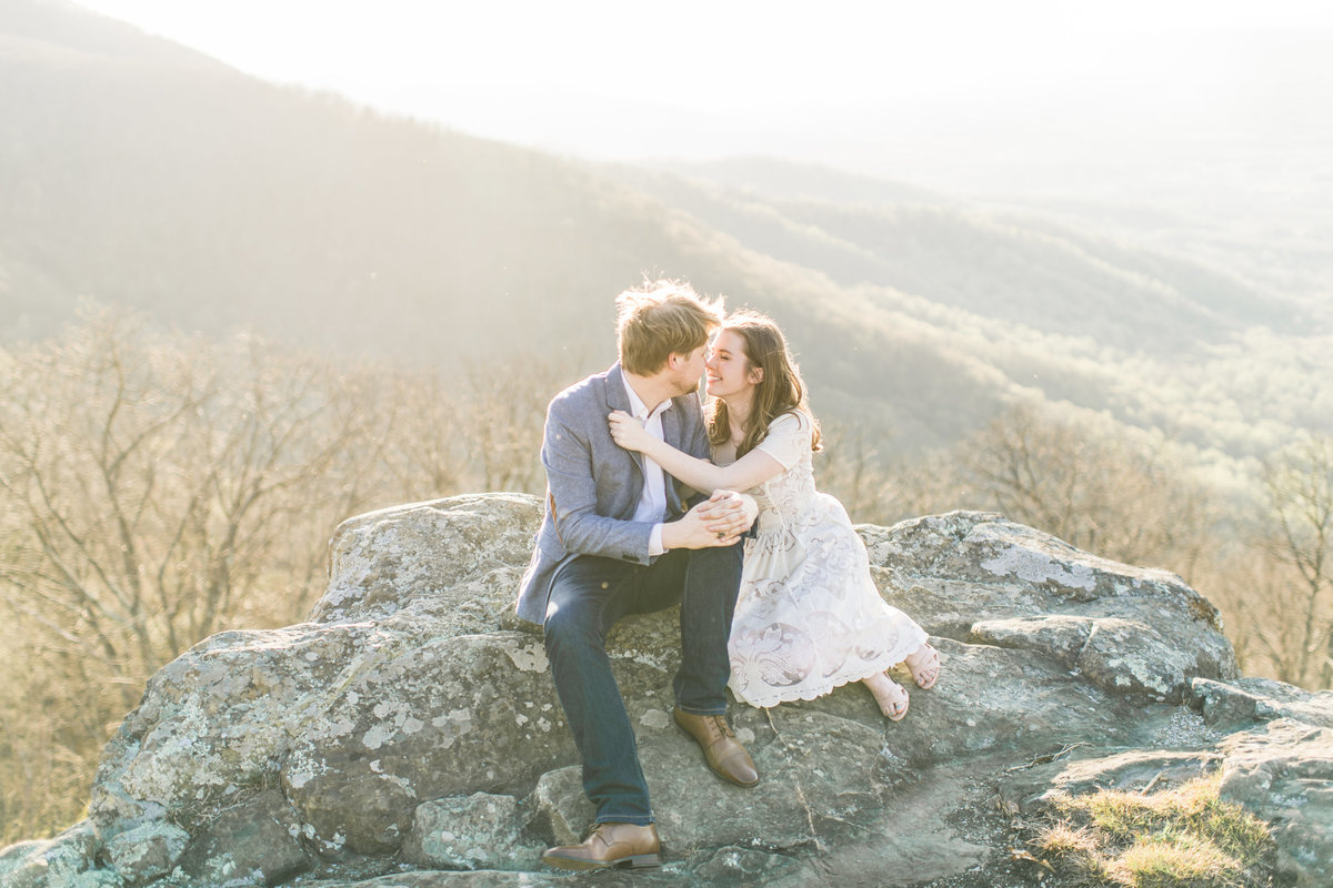 Couple kissing on a rock in the mountains.