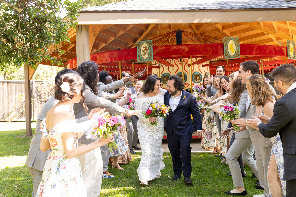 A bride and groom walking through a tunnel of their wedding parties