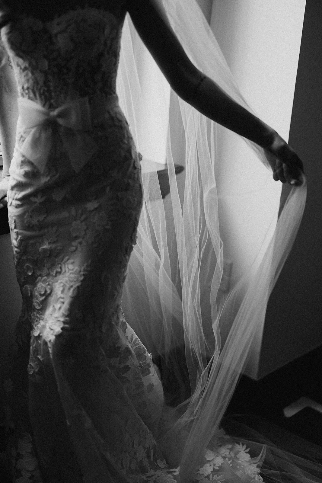 Wedding Photography, black and white images of bride holding out her veil next to a window