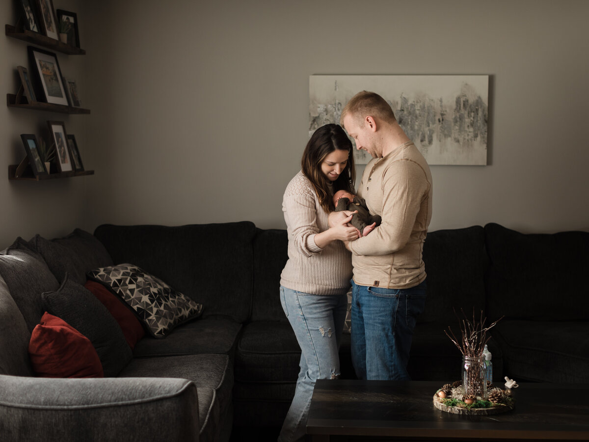 mom and dad holding newborn son in living room for in home lifestyle session