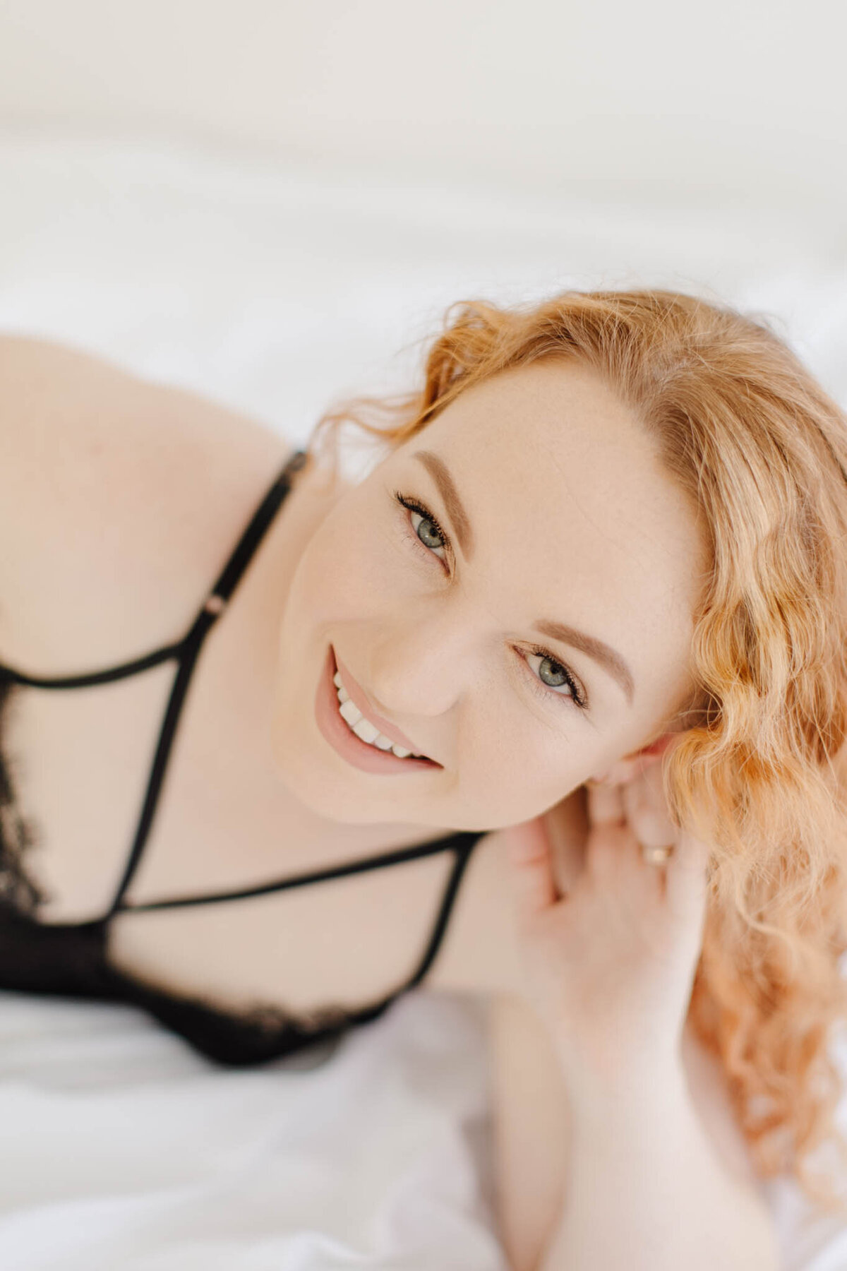 red head woman in black lingerie smiling up at camera