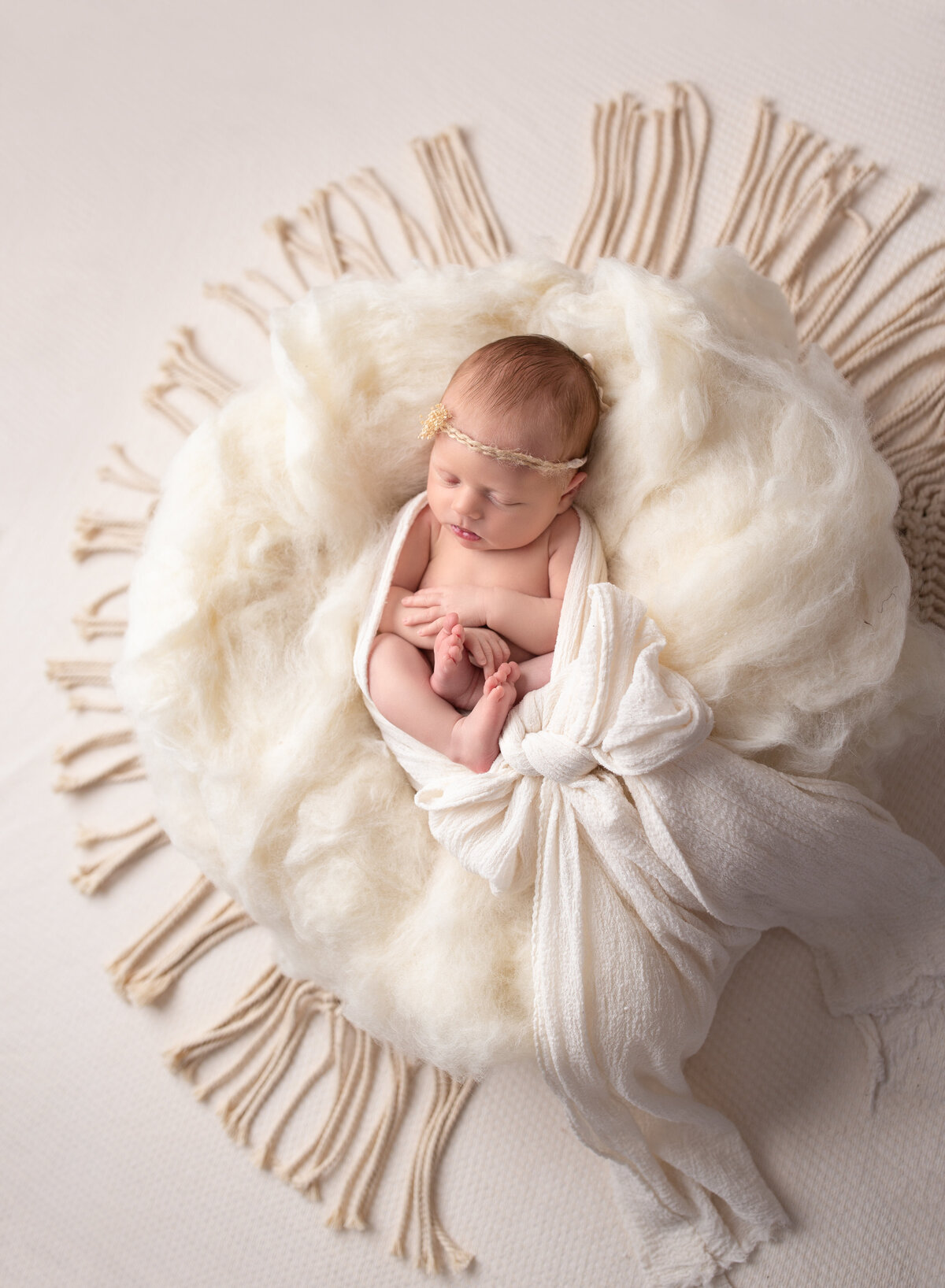 A perfect baby girl on a white cloud of fluff. Photo by Diane Owen.