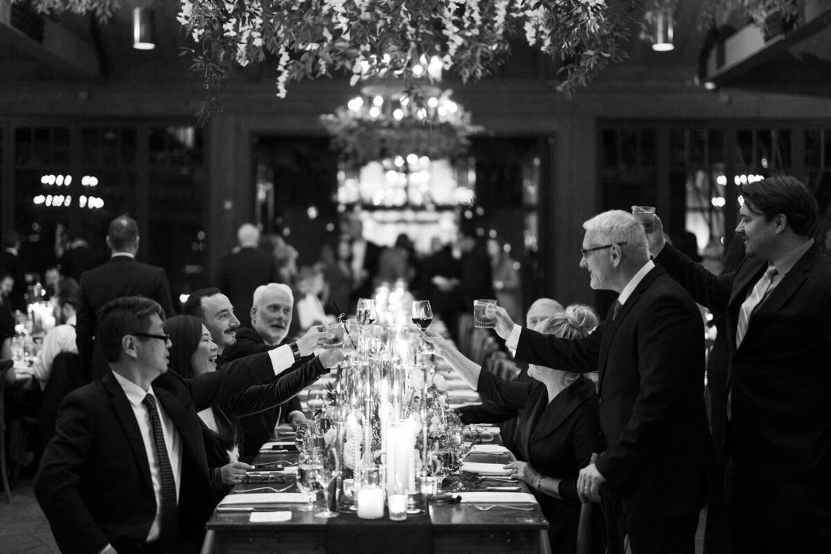 Guests cherring glasses at a wedding reception at The Farm at Old Edwards Inn in North Carolina, by Andrea-Marie Photography
