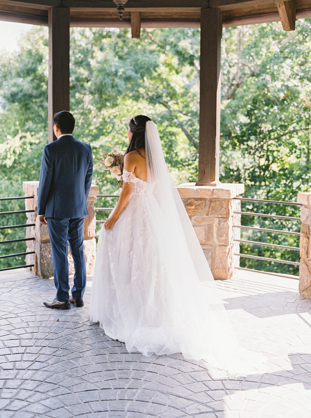 Bride walking toward groom during first look under a stone pavilion at Castle Ladyhawke wedding venue.