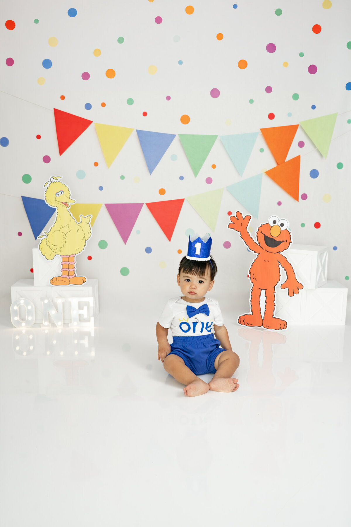 Boy in birthday outfit eating an Elmo cake during themed cake smash session— captured by Alliston and Barrie cake smash photographer.