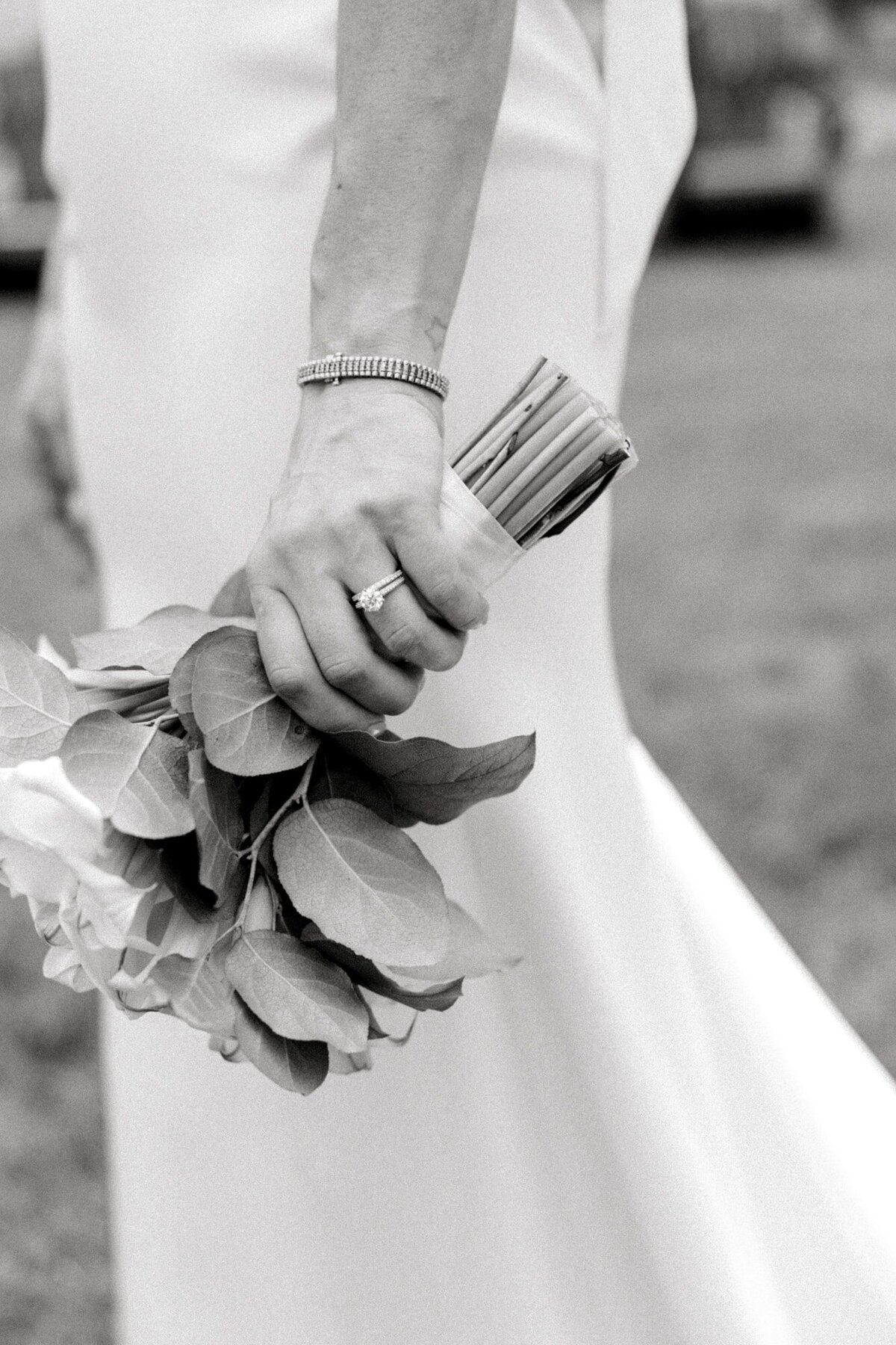 Bride wearing wedding rings and holding bouquet down by side at Farmington Country Club wedding