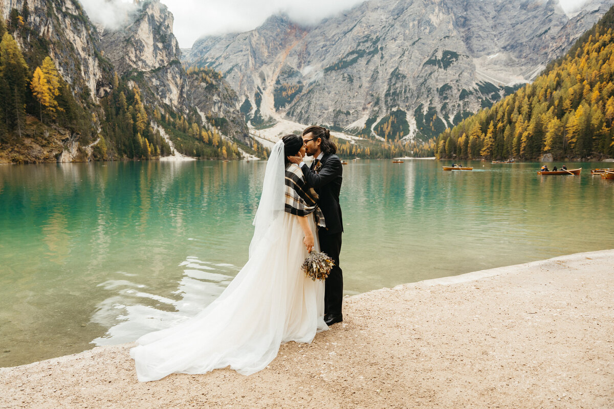Couple kissing together by Lake Braies with mountains