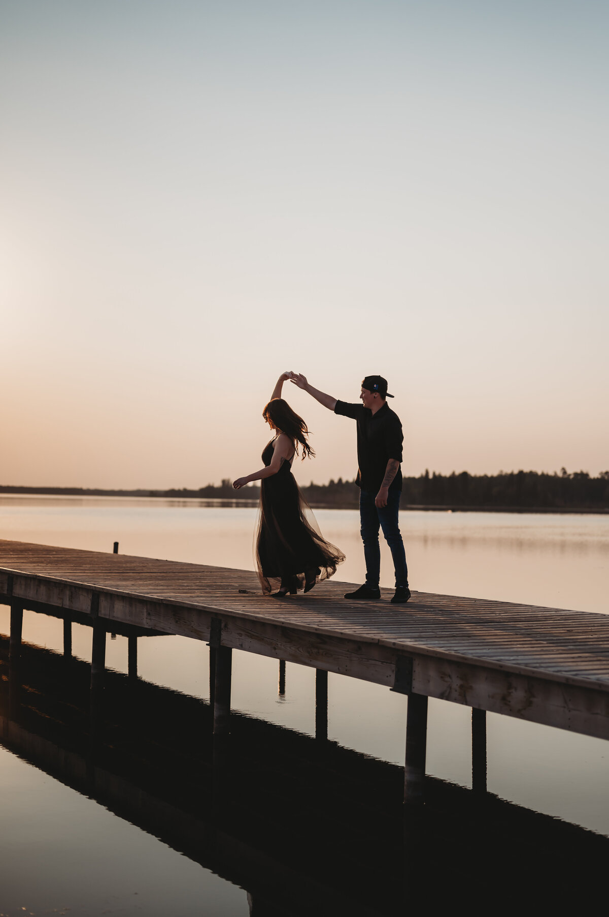 couple dance on a pier and celebrate their engagement