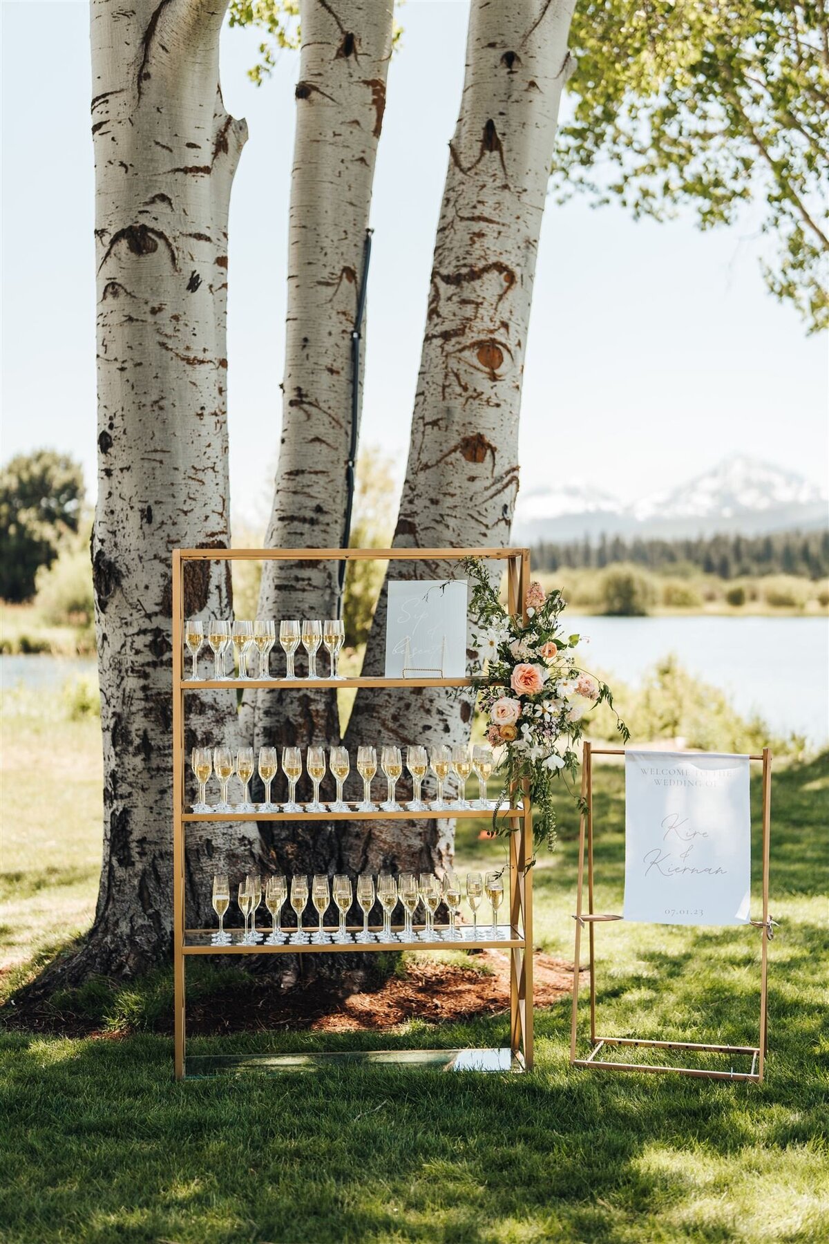 Gold shelf with champagne and flowers with welcome sign on lawn near aspen trees at Black Butte Ranch