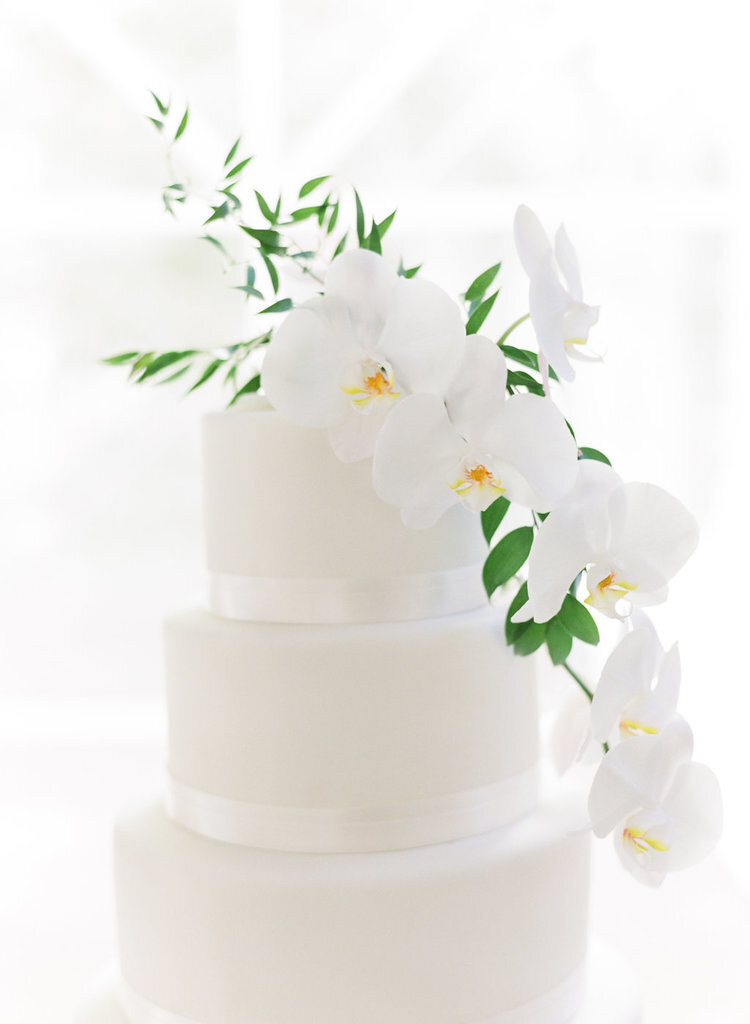 Custom all-white tiered wedding cake with orchid accents