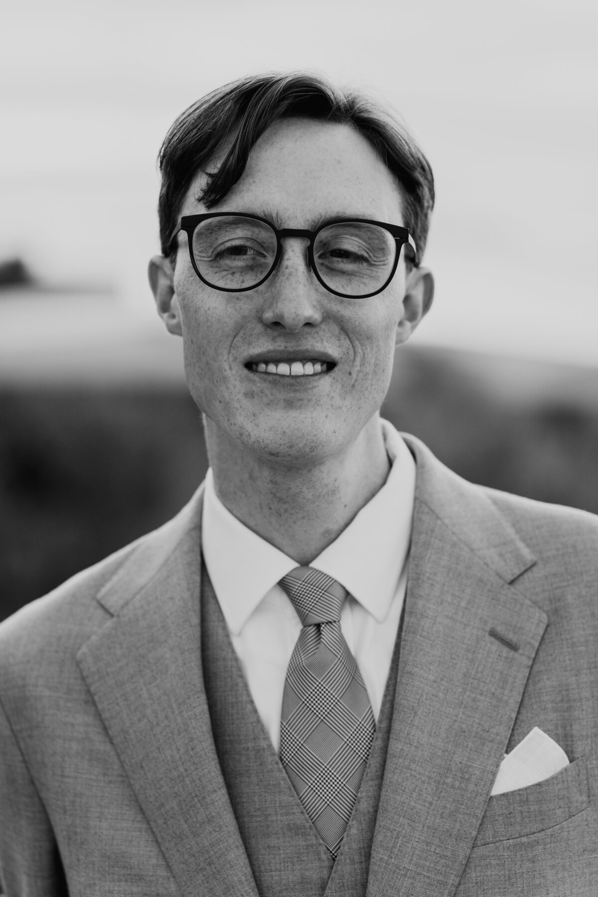 Groom smiling in grey suit and glasses