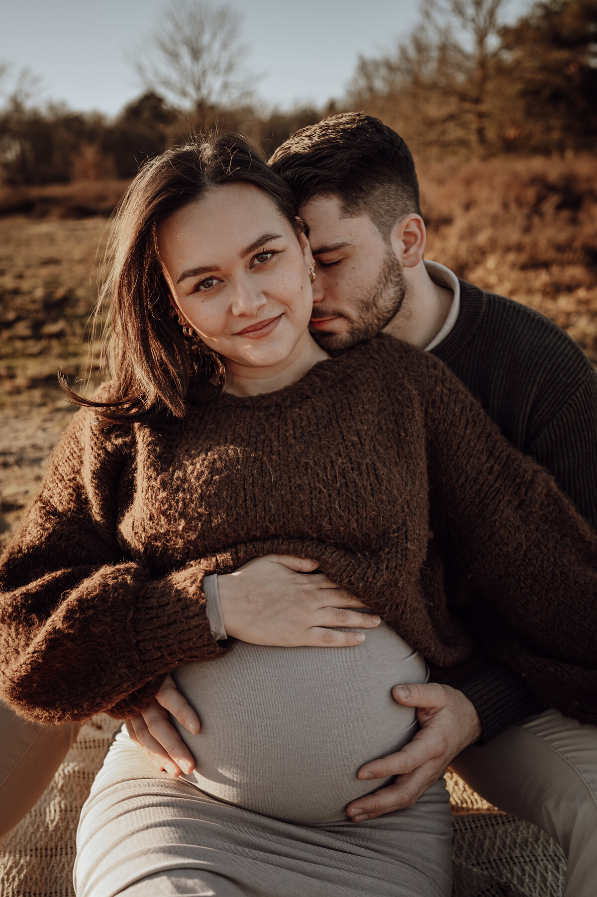 Koppel omhelst elkaar tijdens zwangerschapsshoot op de heide in Antwerpen