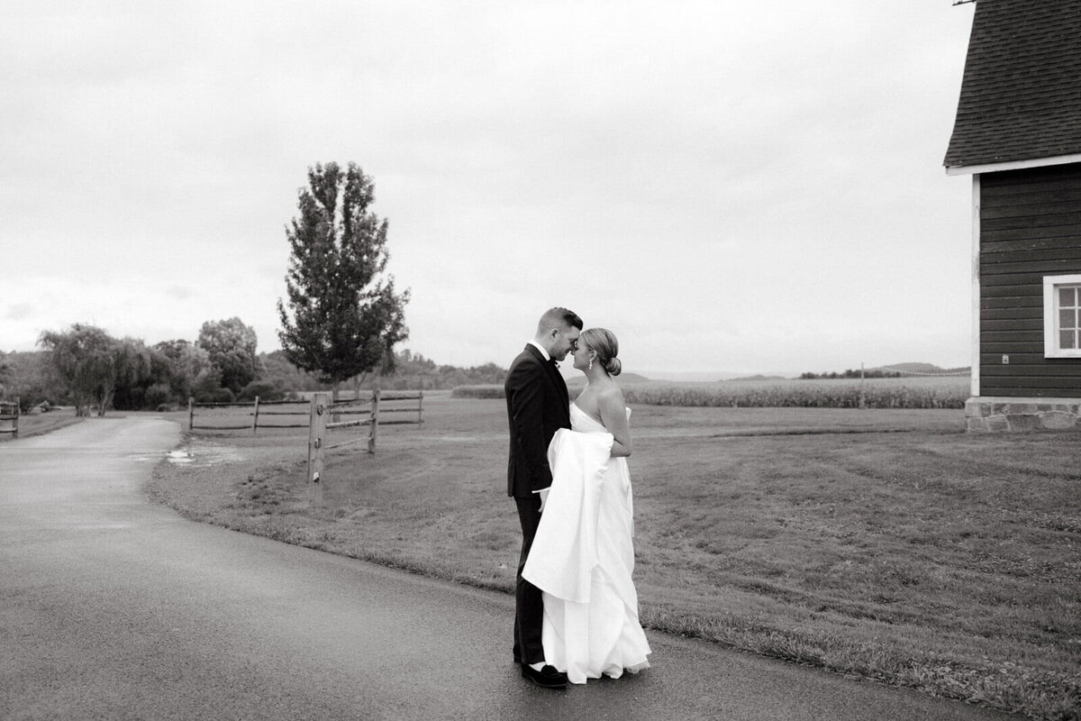 The bride and groom are standing close, heads touching, outdoors at Lion Rock Farm, Sharon, CT.  Image by Jenny Fu Studio
