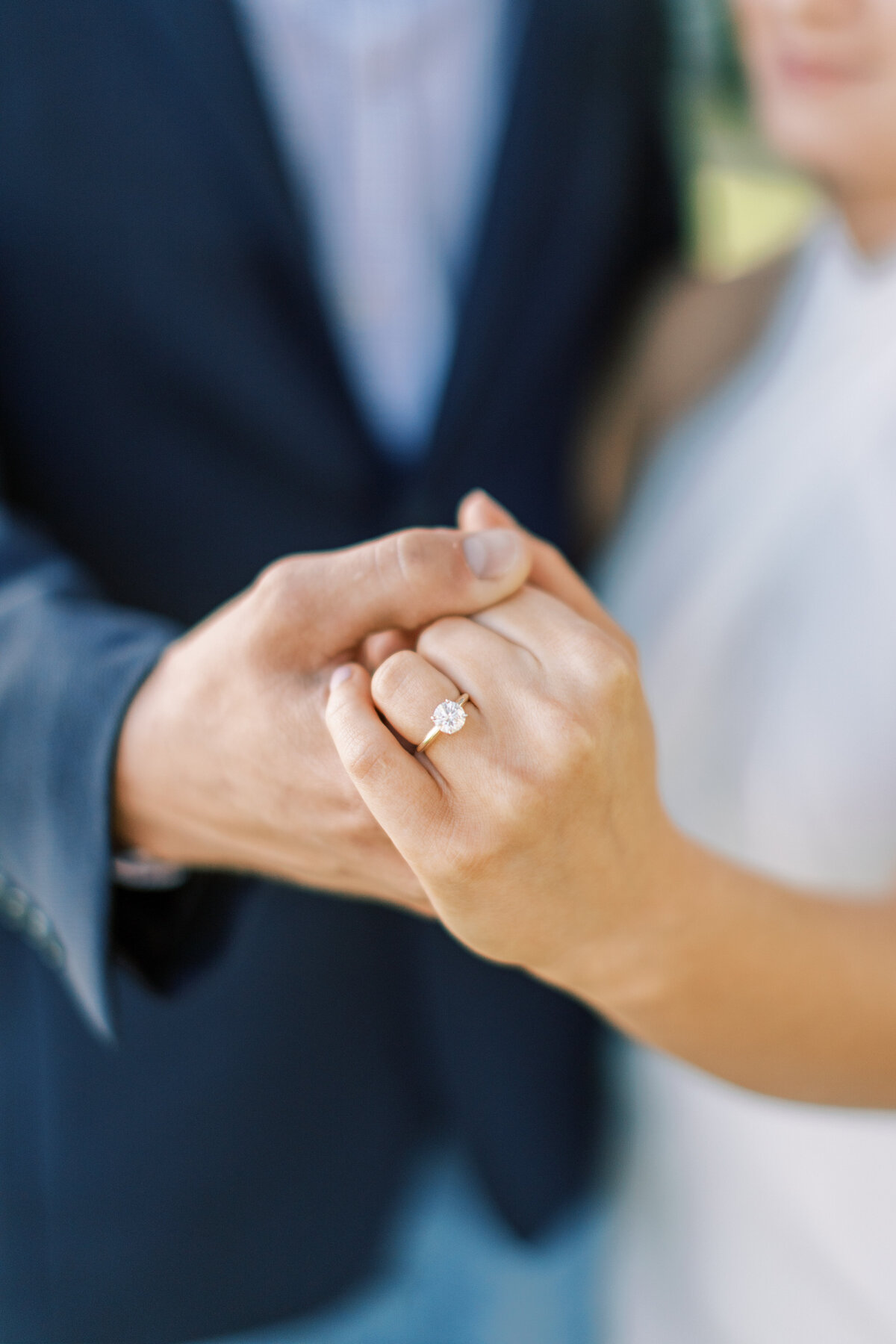 A couple holds their hands out to show off the engagement ring.