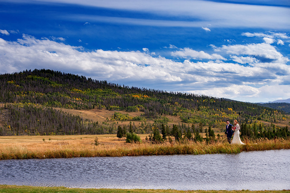 Granby-Colorado-Strawberry-Creek-Ranch-Wedding-Fire-on-the-Mountain-Wedding-Pops-of-Color-Fire-hot-colors-couple-walking-by-the-pond