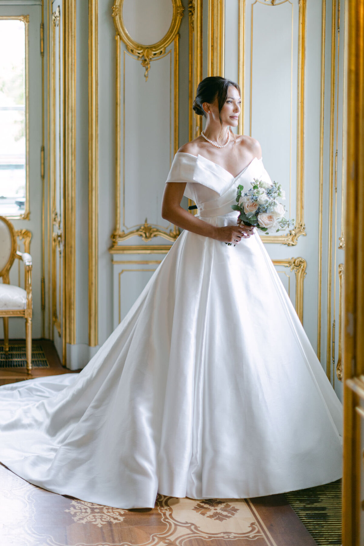 Luxury bride at her bridal portrait standing at the window in white and gold heritage room of palace Coburg
