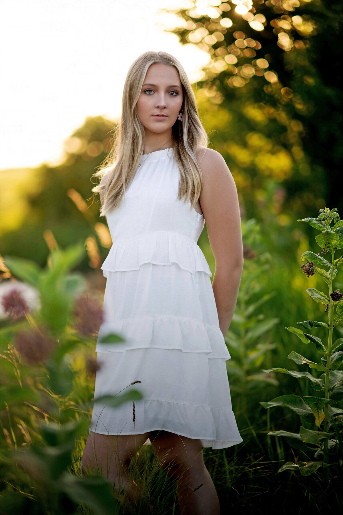 A high school senior stands in a white dress