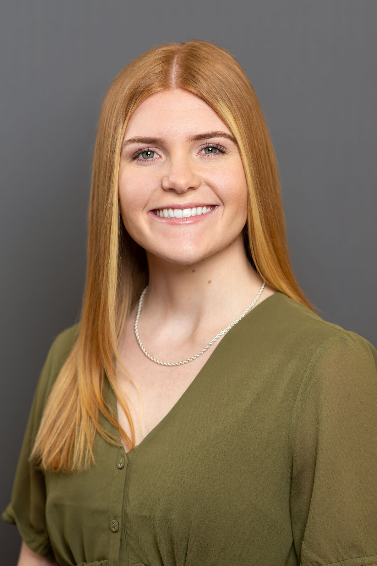 Headshot taken in Salt Lake City Utah of red haired woman against gray backdrop.