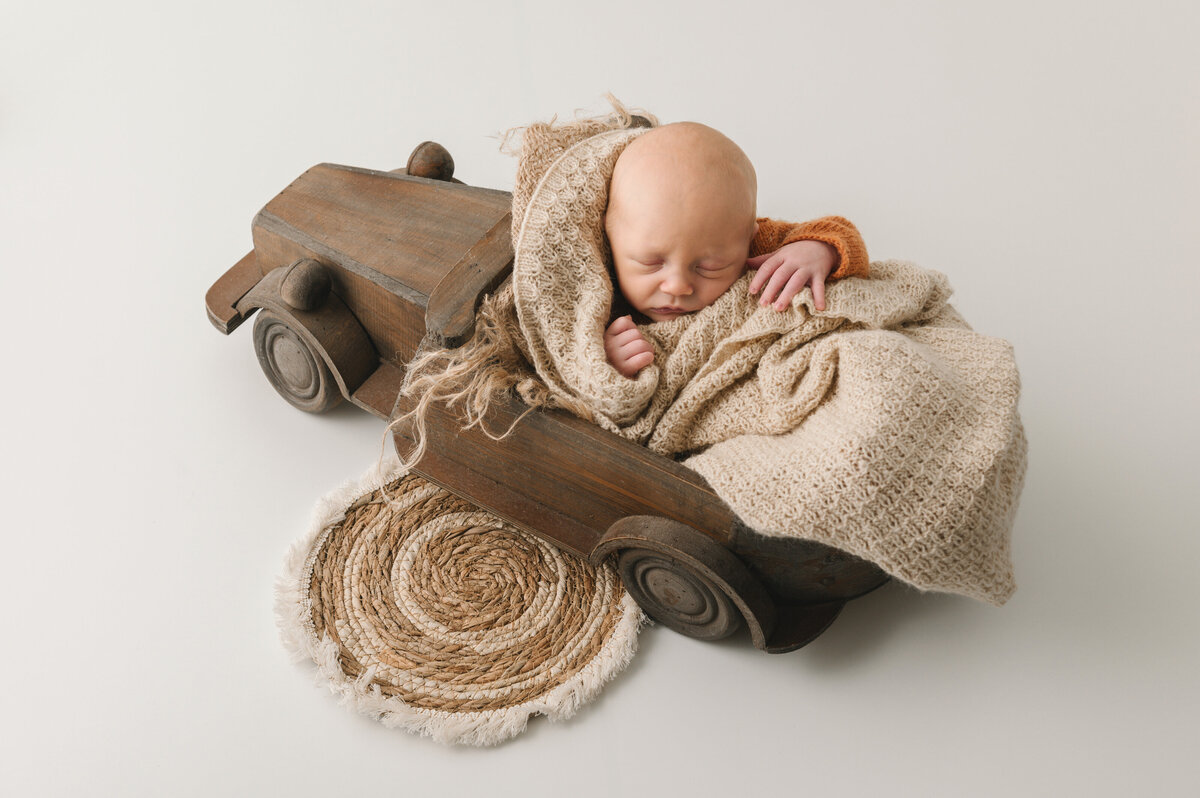 newborn baby jongen geposeerd in auto ingewikkeld in dekens in neutrale setting