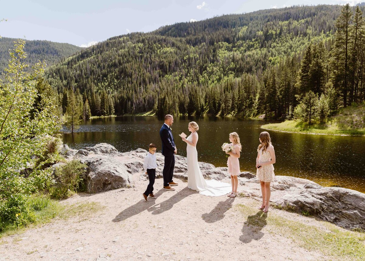 Couple exchanges vows on a rustic wooden bridge surrounded by evergreens during their Silverthorne, Colorado elopement.