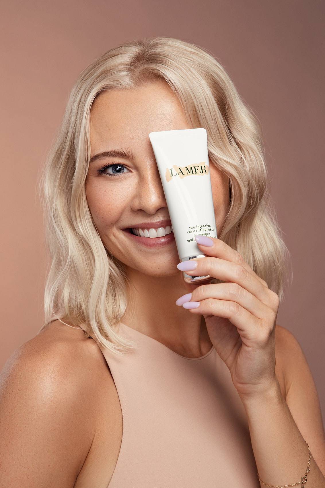 Paulina Michaels in a beauty shot holding a luxury skincare product, exuding elegance, captured by Ylva Erevall.
