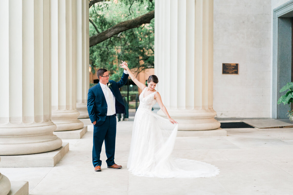 Groom spinning bride in front of columns