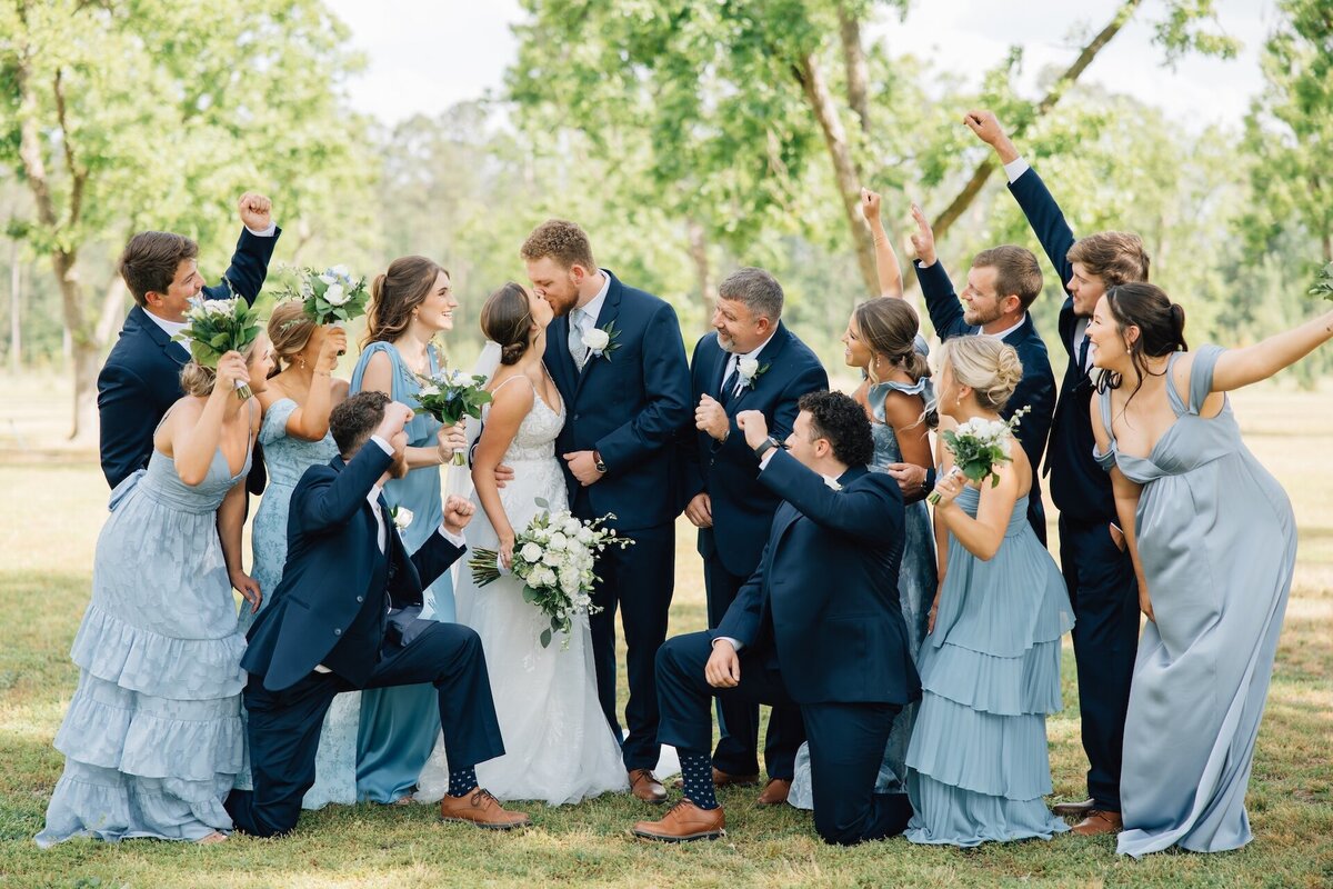 bride and groom kissing as the wedding party celebrates