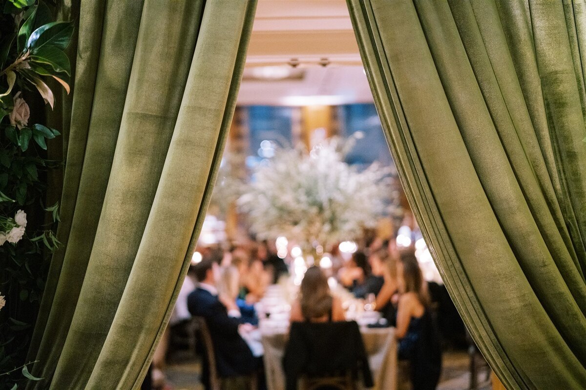 A view of the wedding reception through green drapes.