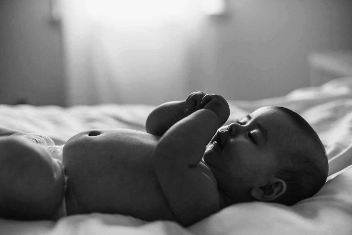 Black and White Image of baby lying on bed