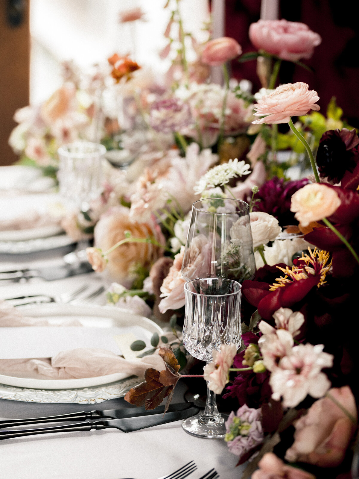 Details of deep red floral centrepieces lining the table at a Chateau St Agnes wedding reception.